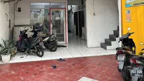 Een gebouw met twee verdiepingen, met een winkelentree op de begane grond, twee motorfietsen ervoor geparkeerd en een trap naar de bovenverdieping.