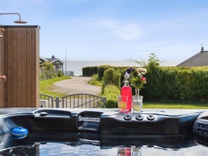 Un jacuzzi con vista al mar, una estructura de madera y un portón que da a una propiedad.