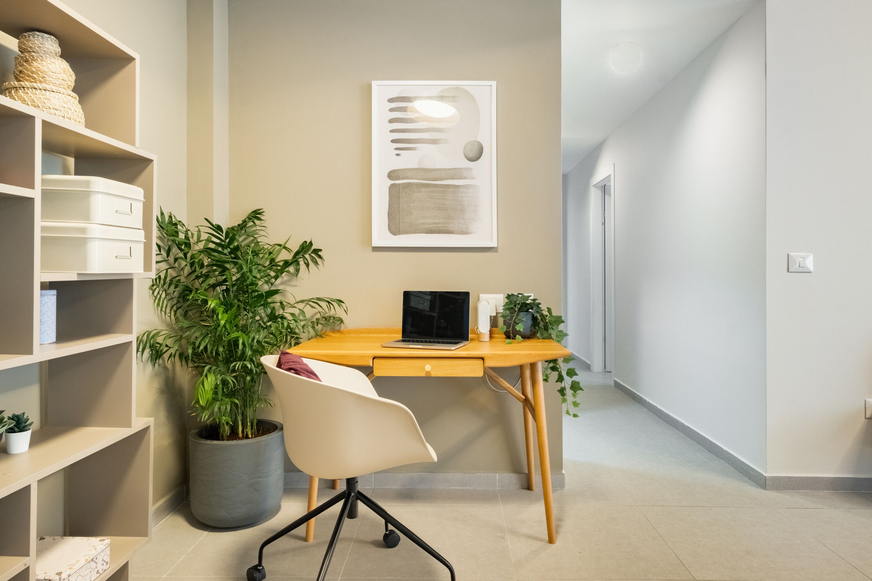 Un espace de bureau moderne avec un bureau en bois, un ordinateur portable et une plante en pot.