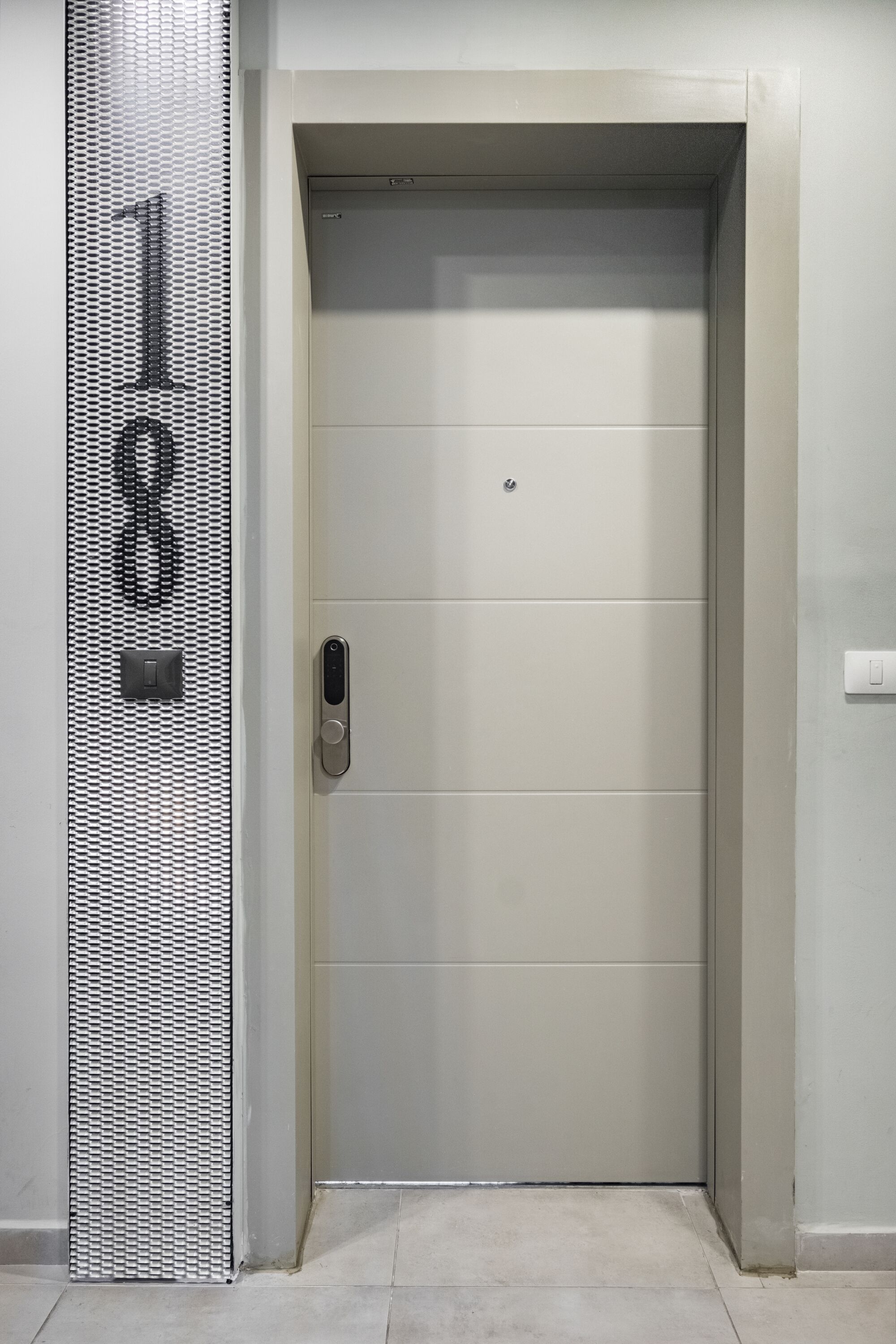 En lukket elevatordør med metalgreb og et lille kontrolpanel.
