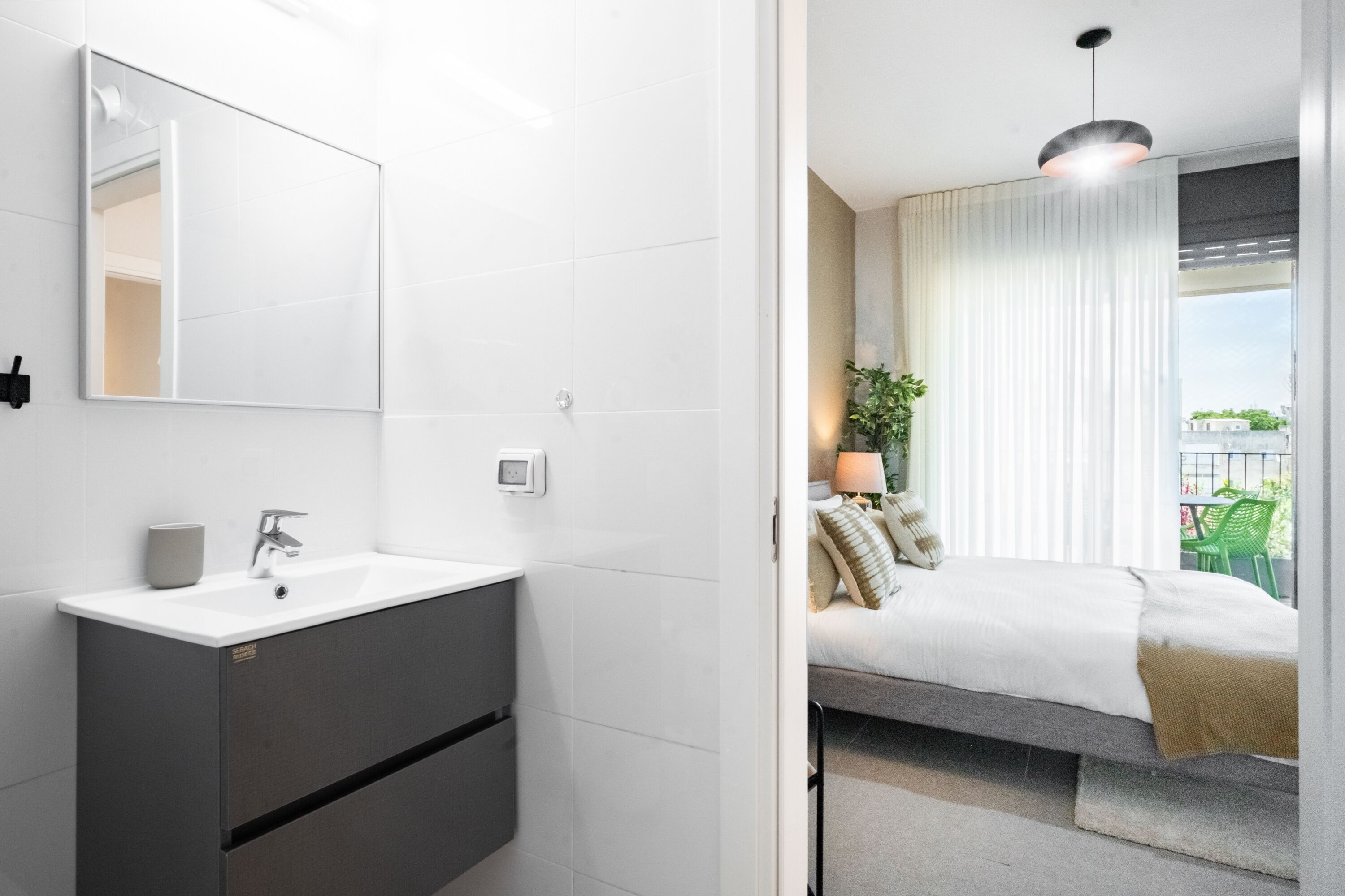 Een moderne badkamer met een wit wastafelmeubel, donker kastje en een grote spiegel.