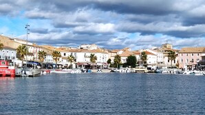 A waterfront with boats docked, buildings with balconies, and palm trees.
