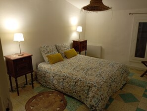 Ein Schlafzimmer mit einem Bett, zwei Nachttischen, einer Lampe, einem Teppich und einem Fenster.