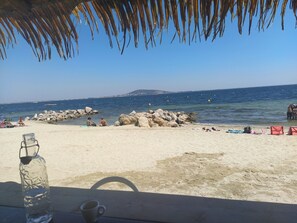 A beach scene with a clear view of the sea, rocks, and distant land. - Duplex La Terrasse Jasmin, 3 Chambres, au Coeur du Centre Historique de Mèze ! (Mèze)