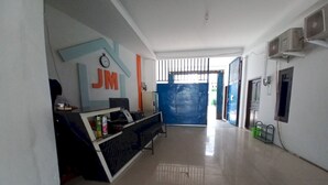 Zona de recepción con mostrador, reloj y una puerta azul que da a la salida.