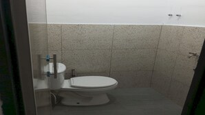 Un baño pequeño y cerrado, con inodoro, zona de ducha y pared de azulejos.