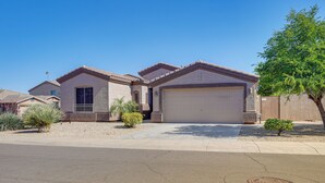 A residential house with a garage, a driveway, and a small tree in the front yard. - Surprise Home w/ Pool & Hot Tub! (Surprise)