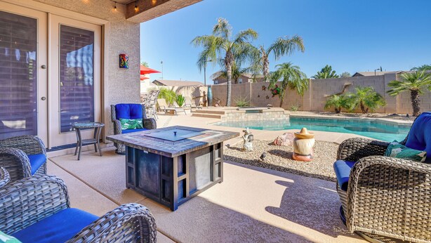 A patio with wicker furniture, a pool, and palm trees. - Surprise Home w/ Pool & Hot Tub! (Surprise)