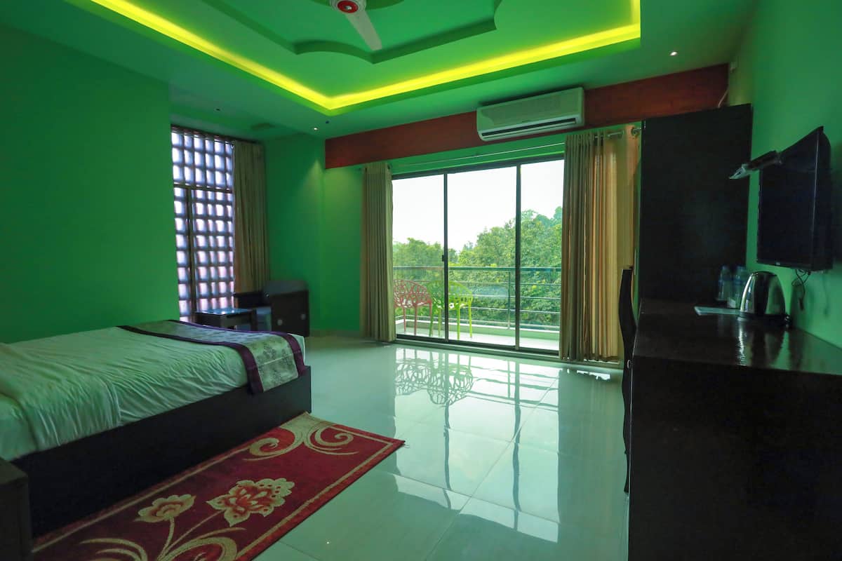 A modern hotel room with a large bed, a TV, a balcony with a view, and a flat-screen TV mounted on the wall.