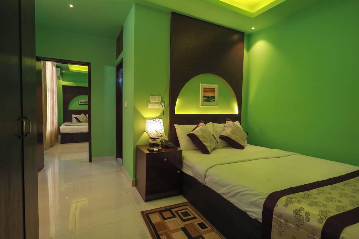A bedroom with a bed, nightstand, lamp, and a picture on the wall.