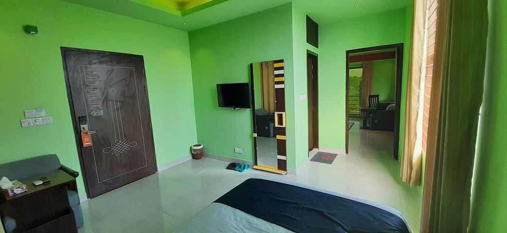 A room with a bed, a desk, a television, and a door with a mirror.