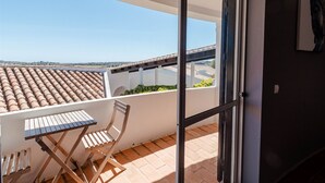 Un balcón con vista a la ciudad, una mesa y una silla.