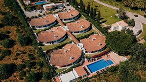 Un resort con varias edificaciones circulares, una piscina y jardines bien cuidados.