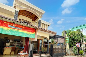 A two-story building with a large banner advertising a restaurant. - OYO 94003 Anjuk Ladang Homestay (Ngaglik)