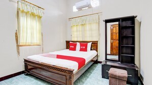 A neatly arranged bedroom with a wooden bed, a small bench, a wardrobe, and a mirror. - OYO 94003 Anjuk Ladang Homestay (Ngaglik)