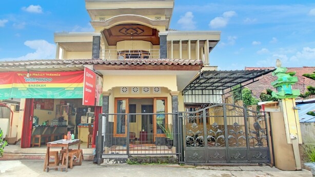 A two-story building with a balcony, a gated entrance, and a storefront with a sign. - OYO 94003 Anjuk Ladang Homestay (Ngaglik)