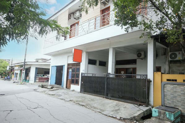 A two-story building with a balcony, a gated entrance, and a visible air conditioning unit. - SPOT ON 94033 Harapan Jaya (Bekasi)