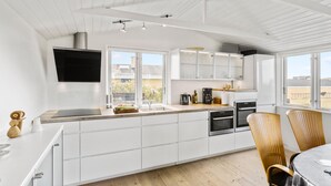 Eine moderne Küche mit weißen Schränken, einem eingebauten Backofen und einem großen Fenster.