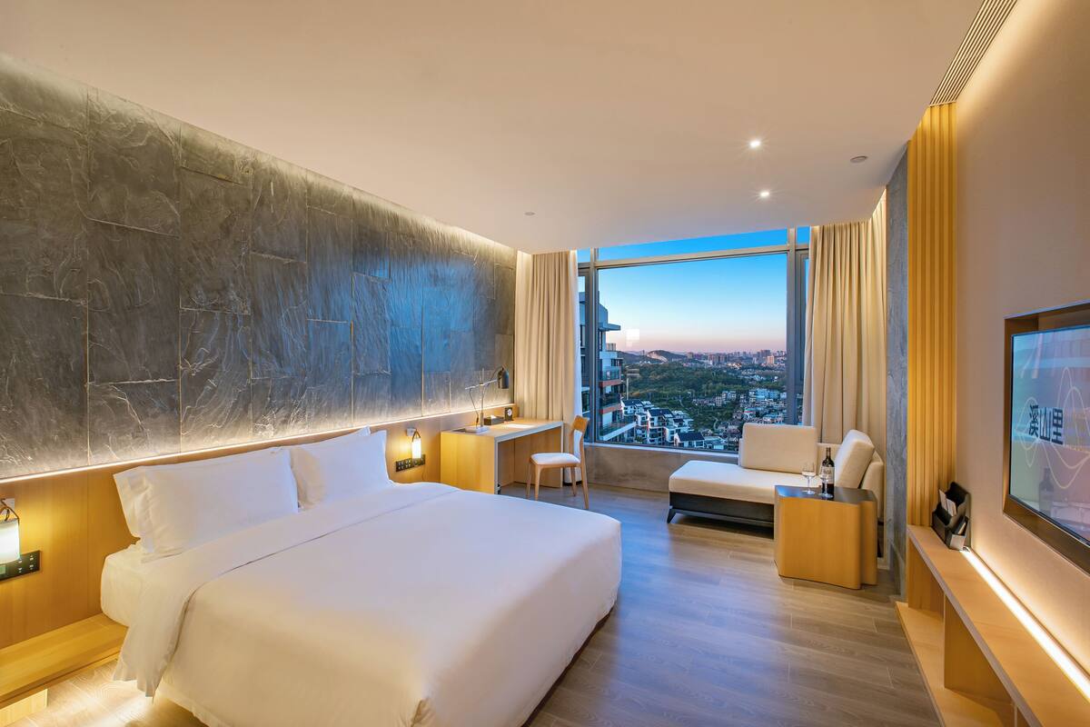 Une chambre d’hôtel moderne équipée d’un grand lit, d’un bureau, d’une chaise, d’un canapé et d’une télévision.