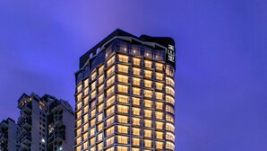 Un hôtel de grande hauteur au design moderne, caractérisé par une façade incurvée imposante et des fenêtres illuminées.