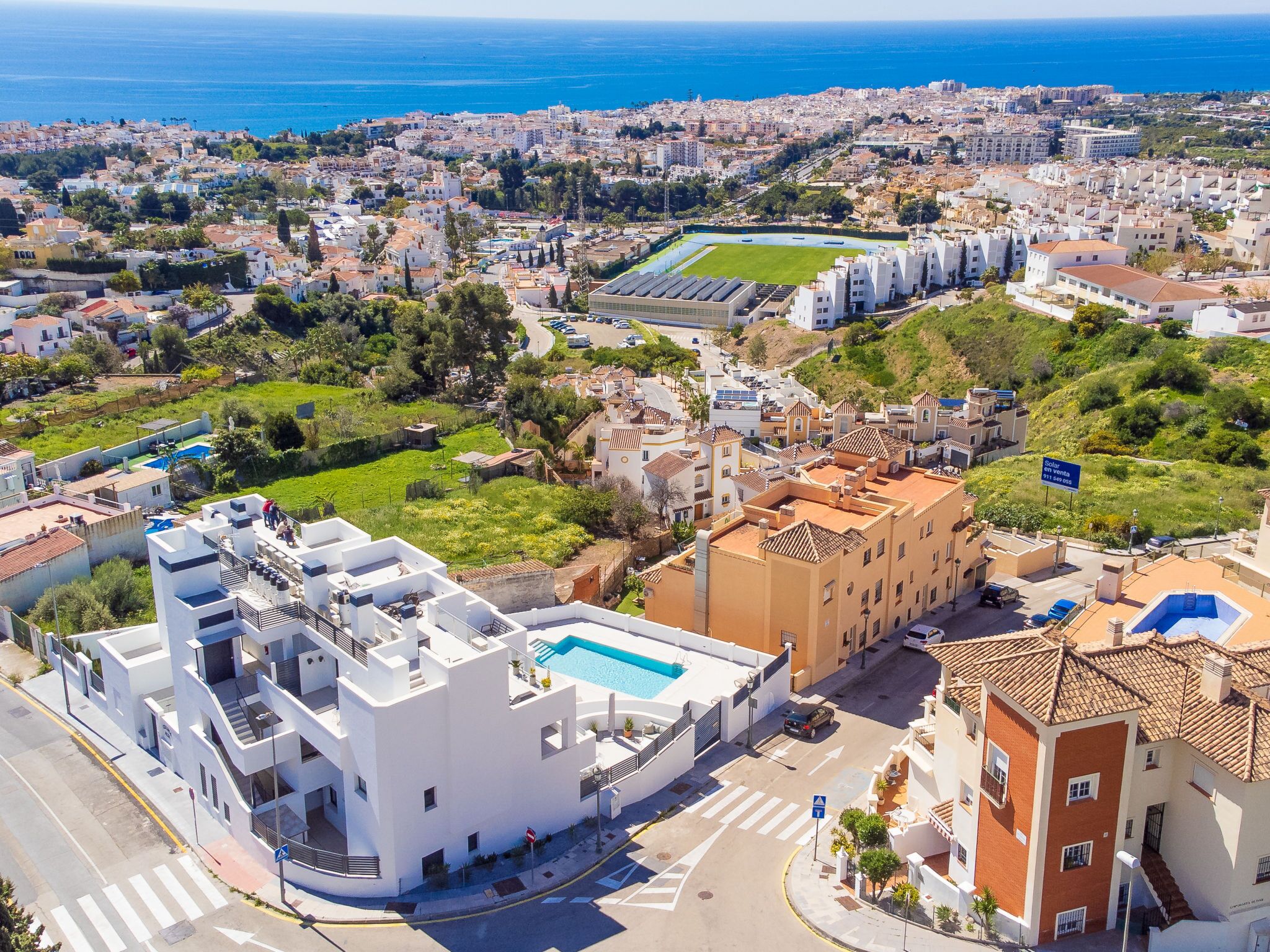 Una zona residencial costera con edificios modernos, una piscina y vistas al mar.
