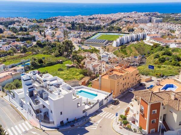 Un quartier résidentiel en bord de mer, avec des bâtiments modernes et traditionnels, une piscine et une vue sur la mer.