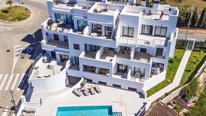 Ein modernes, mehrstöckiges Gebäude mit Pool auf dem Dach und Außenbereichen zum Sitzen.