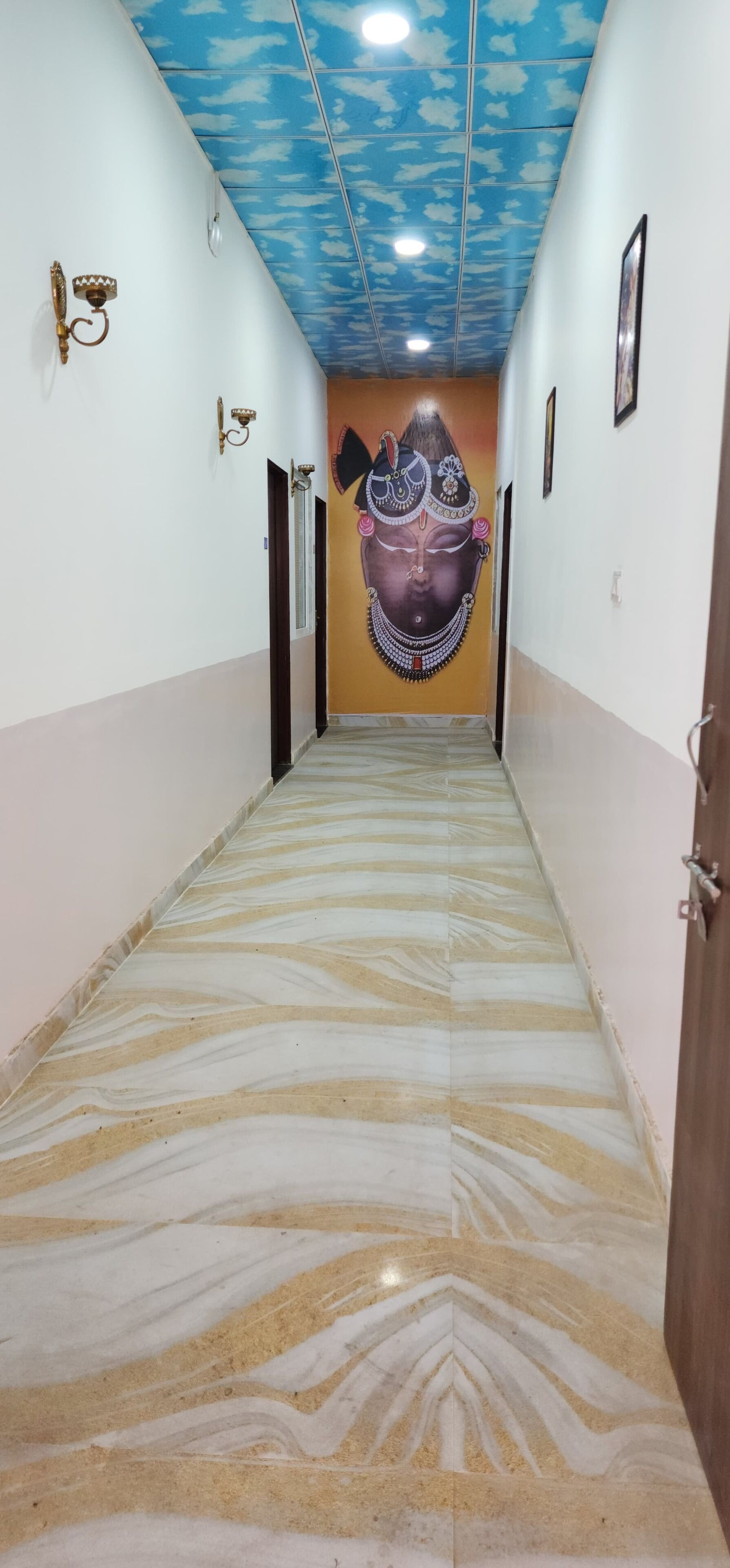 A hallway with a patterned floor, a mural on the wall, and a ceiling with a cloud design.