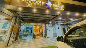 The exterior of AIC Rooms Hall with a neon sign, a checkered floor, and a parked car. - Shree Keshav Haweli (Sikar)