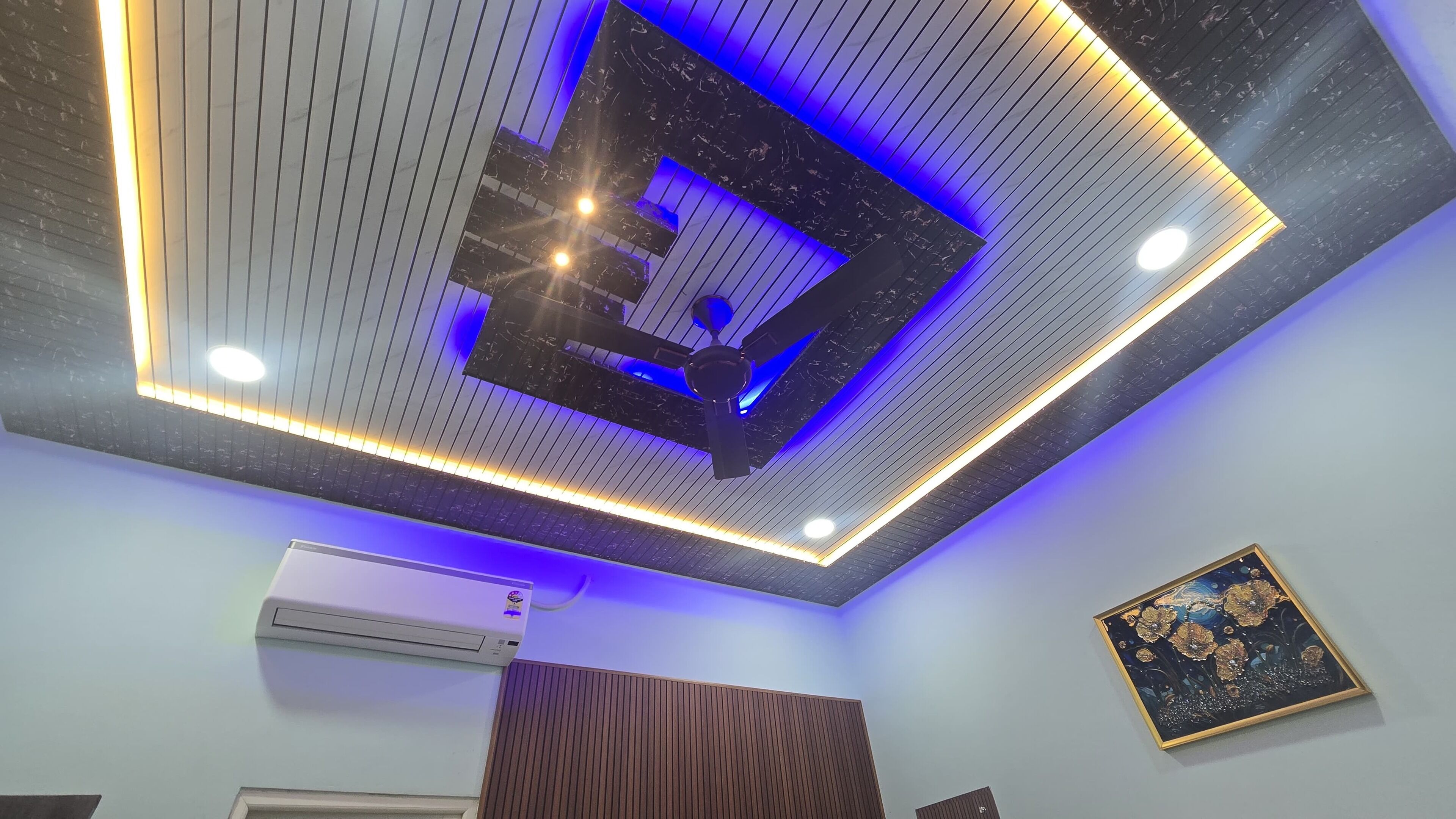 Een modern plafond met inbouwverlichting en een centrale ventilator.