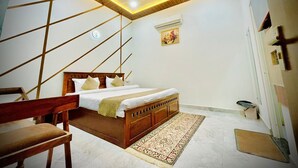 A bedroom with a wooden bed, a bench, a patterned rug, and a ceiling with recessed lighting. - Shree Keshav Haweli (Sikar)