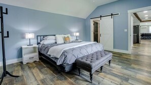 A bedroom with a bed, bedside tables, a ceiling fan, and a sliding door leading to another room. - Boondock Retreat, pet friendly 4 bedroom home with EV charger (Himrod)