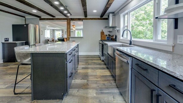 A modern kitchen with a large island, stainless steel appliances, and a view of the outdoors through large windows. - Boondock Retreat, pet friendly 4 bedroom home with EV charger (Himrod)