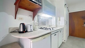 A compact kitchen with a microwave, toaster, coffee maker, and a gas stove. - Cozy Studio in Palermo with Private Patio! (Buenos Aires)
