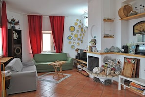 A living room with a green sofa, a grey armchair, a wooden coffee table, a television, and a fireplace. - Villa Giulia Resort with private pool and stunning sea views (Provincia di Latina)