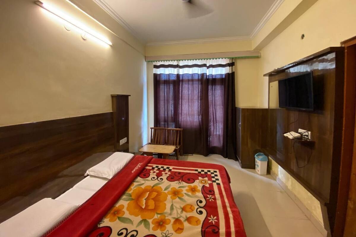 Una habitación de hotel con una cama, una silla, un televisor y un ventilador de techo.