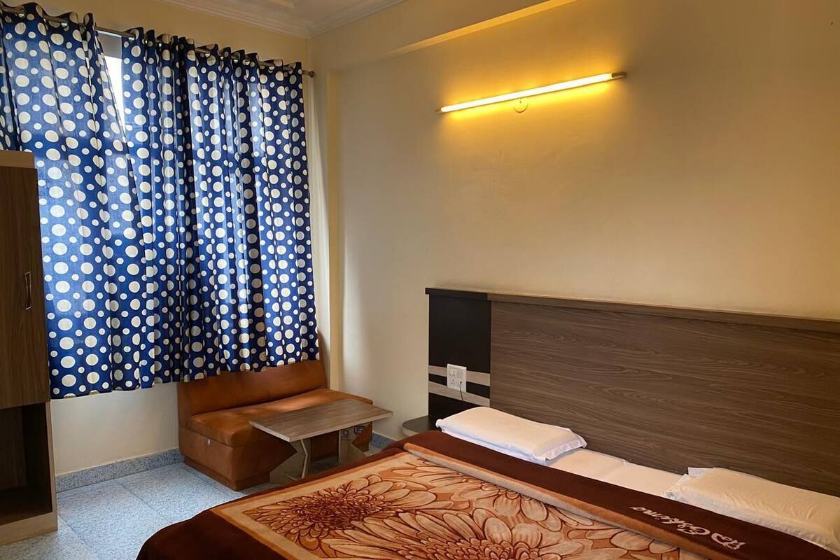 Habitación de hotel con cama, sofá, una mesita y cortina de lunares.