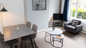 A modern living room with a dining table, sofa, and a TV.