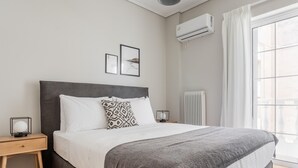 Une chambre bien rangée, avec un grand lit, des tables de chevet, un radiateur et une fenêtre avec des rideaux.