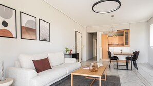Un salon moderne avec un canapé blanc, une table basse et des œuvres d’art accrochées au mur.