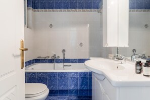 A bathroom with a bathtub, two sinks, a toilet, and a mirror. - Spacious Serenity in Marousi (Marousi)