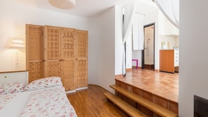 A bedroom with a bed, wooden wardrobe, and a bathroom with a shower and toilet. - Apartments Ilija Njavro (Crikvenica)