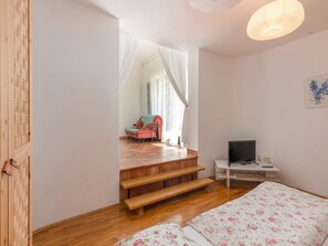 A bedroom with a bed, a TV, a desk, and a chair. There is a staircase leading to another room.