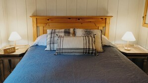 A bed with a wooden headboard, two bedside tables with lamps, and a clock on one table. - Tranquil cabin with WiFi in charming Wasilla (Wasilla)