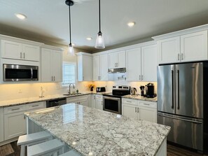 A modern kitchen with white cabinetry, stainless steel appliances, and a granite countertop. - Luxury Medical District Home, EV Charger, Gated #1 (Augusta)