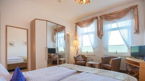 A hotel room with two beds, a desk, a chair, a TV, and a large mirror.