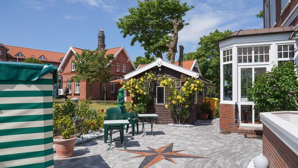 A courtyard with a star-shaped pavement, green chairs, and potted plants.