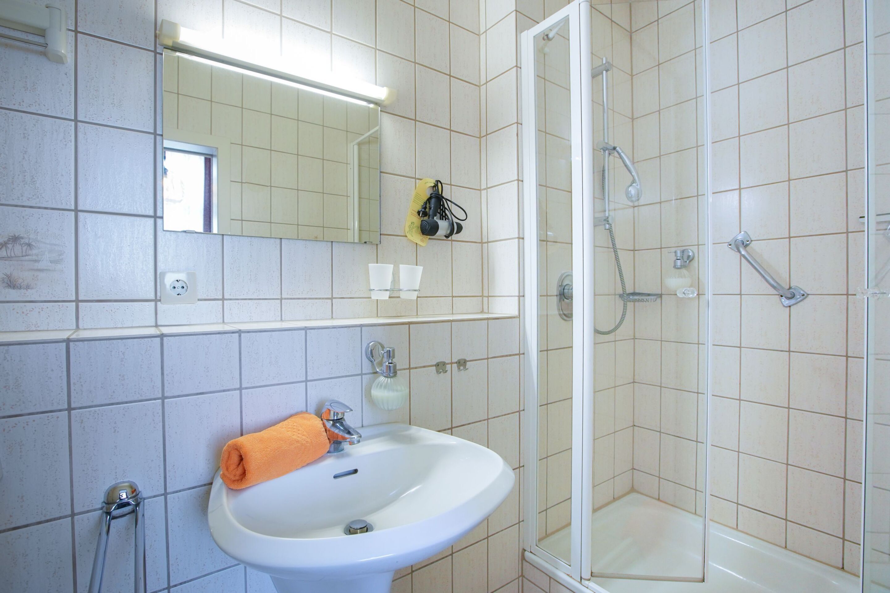 A bathroom with a sink, mirror, and shower.