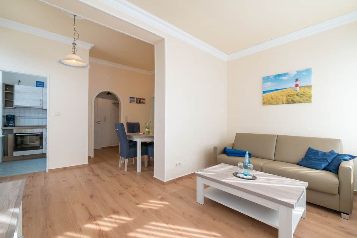 A modern living room with a sofa, a coffee table, and a dining area with a table and chairs.