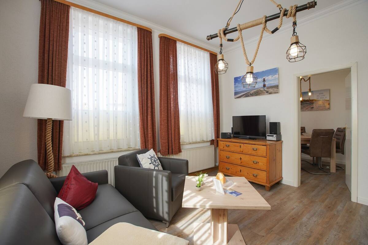 A modern living room with a sofa, a wooden table, a TV, and a dining area.